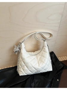 Close-up of white quilted leather crescent bag with silver star pendant and chain strap