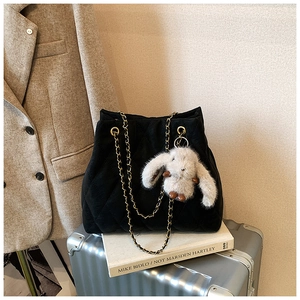 Détail d'un cabas matelassé noir avec chaîne dorée et breloque lapin en peluche doux