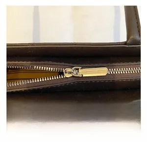 Detailed close-up of premium metal zipper and smooth dark brown leather texture