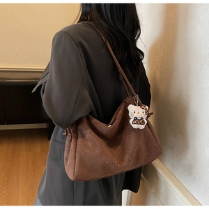 Détail d'un sac cabas en daim marron avec gaufrage CHRSDN et breloque peluche