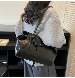 Detail view of large black tote bag with silver buckle and smooth PU leather texture