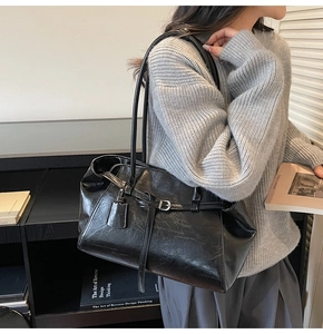 Detail of black glossy PU leather tote bag with silver buckle and stylish shoulder strap