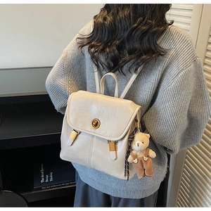 Detail of off-white retro PU leather backpack with gold clasp and brown bear keychain charm