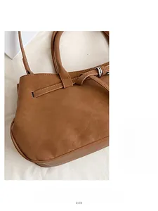 Detail of brown PU leather handbag featuring slim handle and buckle strap decorative stitching