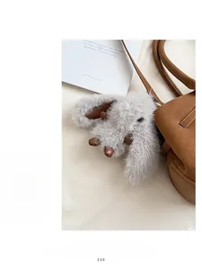 Close-up of a grey plush rabbit charm with leather ears attached to a brown leather bag