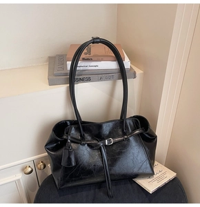 Detail of black vintage tote bag featuring glossy wrinkled leather and metal buckle hardware