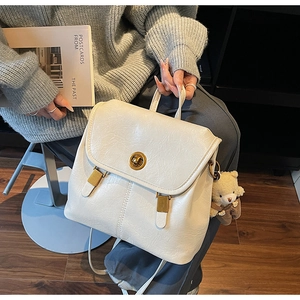 Close-up of retro white backpack with gold twist lock and cute teddy bear pendant charm