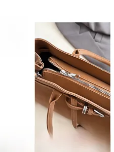 Close-up of smooth silver metal zipper on premium brown leather shoulder handbag detail