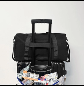 Travel bag with integrated trolley sleeve secured on a rolling suitcase handle