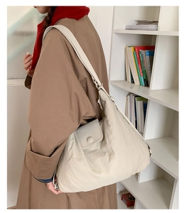 Detailed view of beige padded tote bag with quilted texture worn by model for daily commute