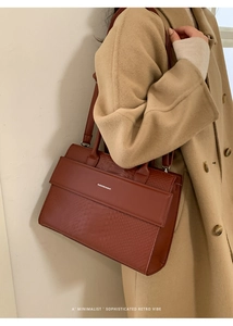 Close-up of brick red crocodile texture handbag featuring an elegant metal clasp detail