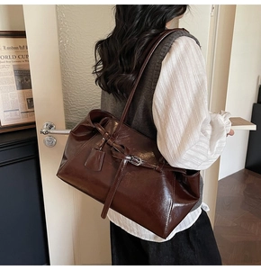 Detail view of large dark brown oil-waxed leather tote bag with stylish buckle strap details