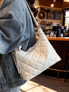 White quilted large tote bag with silver chain straps shown in a lifestyle cafe setting