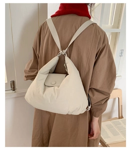 Detail of a creamy puffer backpack featuring a quilted texture and wide shoulder straps