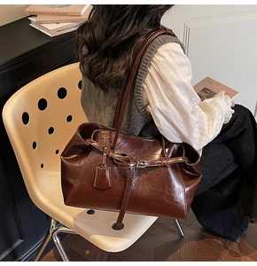 Detail of dark brown oil wax leather tote bag with buckle and long shoulder strap