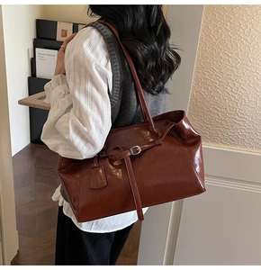 Detail of vintage brown leather tote bag with elegant buckle strap and glossy finish
