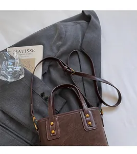 Detail of adjustable strap and gold rivets on a vintage dark brown bucket bag