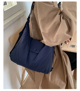Detail of navy blue nylon tote bag with matching round button and adjustable strap