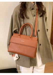 Detailed view of crocodile embossed brown handbag styled with a classic trench coat