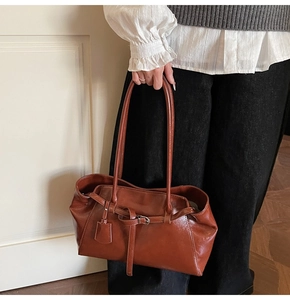Detail view of brown vintage leather tote with slim shoulder straps and metal buckle charm