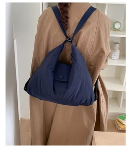 Detail of navy quilted puffer backpack with flap closure and adjustable webbing straps
