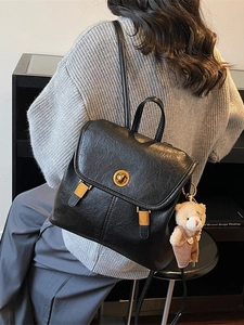 Vintage black leather backpack for women featuring a gold twist lock and a cute bear charm