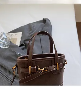 Detailed close-up of dark brown bucket bag with golden metal buckle and sleek leather texture