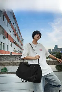Outdoor model display of a large black fitness travel bag with adjustable shoulder strap