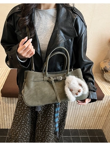 Detail of dark green matte leather bag with silver buckle and plush bunny charm