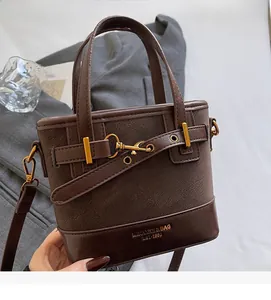 Detail of dark brown vintage bucket bag featuring textured faux leather and metal buckle strap