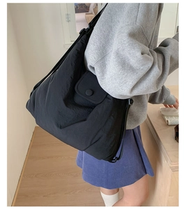 Side view of large black padded tote bag on model showing size and adjustable strap