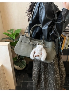 Close-up of retro dark green matte shoulder bag with a cute white plush bunny charm