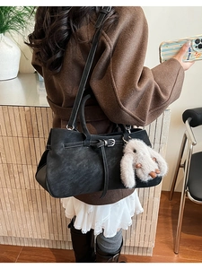 Detail of black large shoulder bag with matte finish and cute grey plush bunny pendant