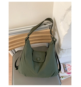 Detailed view of the dark green quilted nylon tote bag placed on a grey chair