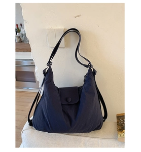 Detailed shot of dark blue nylon hobo bag featuring snap button flap and versatile straps