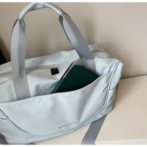 Close-up of light blue nylon travel bag with front pocket, handles, and adjustable strap