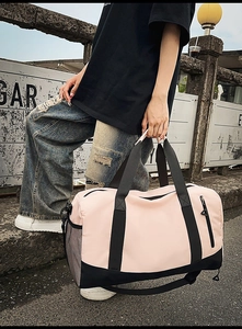 Pink and black large capacity gym bag with side mesh pocket shown in outdoor setting