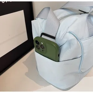 Close-up of the light blue travel bag side pocket holding a smartphone for storage