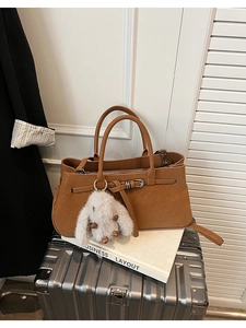 Detailed side view of a brown tote bag featuring a plush rabbit charm and buckle strap