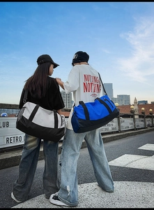 Two models showcasing large fitness travel bags with separate shoe compartments outdoors