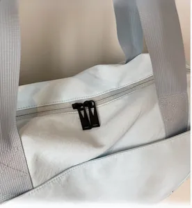 Detail view of the smooth dual black zippers and grey handles on light blue travel bag