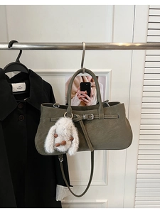 Detail of olive green vintage handbag featuring metal buckle and plush bunny charm