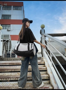 Outdoor lifestyle shot of a woman carrying a black and white duffel bag on stairs