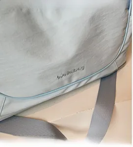 Close-up of light blue waterproof nylon travel bag with Wellalbag logo and fabric strap