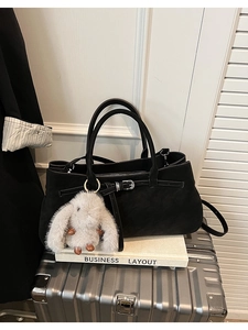 Detail of black matte handbag with silver buckle and cute gray plush bunny pendant