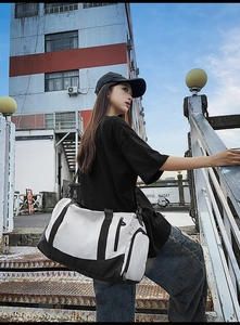 Detail of a black and white sports bag featuring side zipper pocket and wide strap
