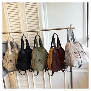 Waterproof nylon backpacks shown in khaki, black, green, brown, and grey on a metal rack