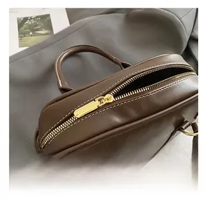 Close-up of dark brown leather handbag with gold hardware and white contrast stitching