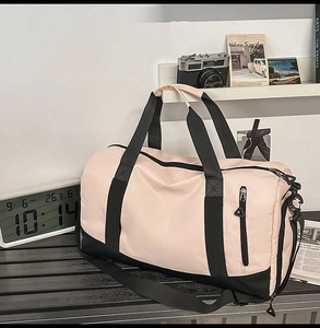 Detailed view of pink sports duffel bag with black straps and side zipper pocket