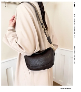Gros plan d'un sac demi-lune marron foncé avec une bandoulière jacquard géométrique